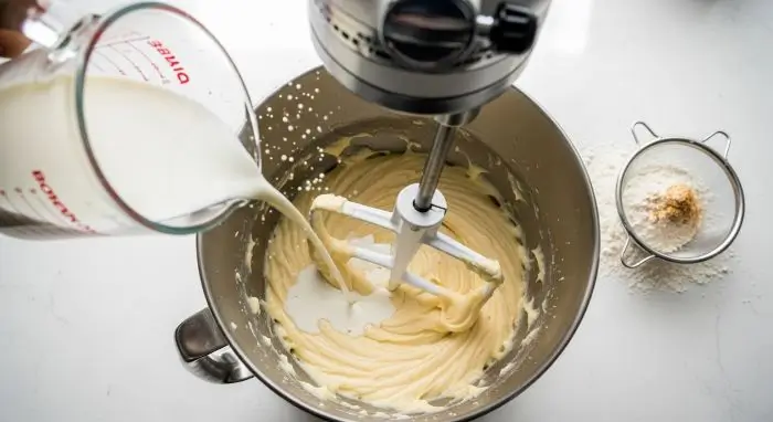 Alternating wet and dry ingredients for the best funfetti cake recipe, buttermilk poured into silky batter for a moist, tender crumb.